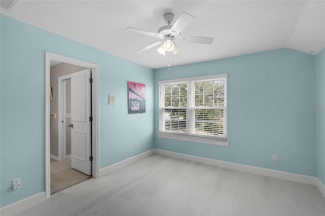 unfurnished bedroom featuring ceiling fan, vaulted ceiling, a textured ceiling, and light hardwood / wood-style floors