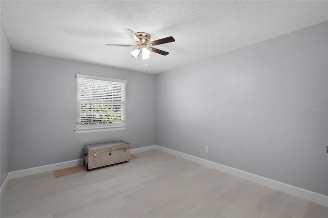 spare room featuring ceiling fan, light hardwood / wood-style floors, and a textured ceiling