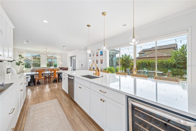 kitchen featuring hanging light fixtures, white cabinetry, sink, and beverage cooler