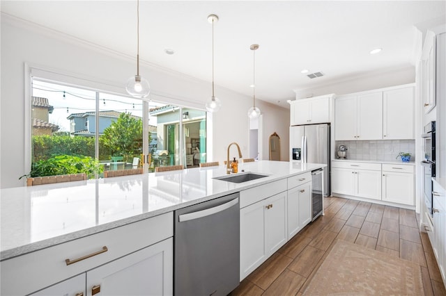 kitchen with decorative light fixtures, sink, white cabinets, stainless steel appliances, and light stone countertops