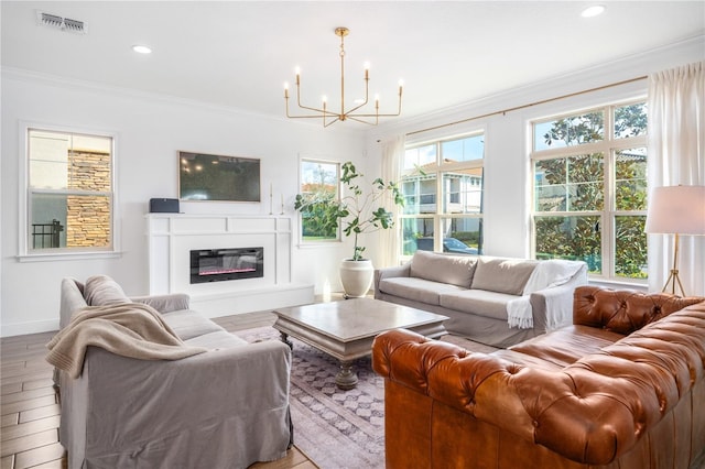 living room with an inviting chandelier, crown molding, and light hardwood / wood-style floors