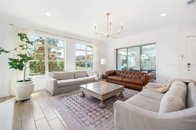 living room with crown molding, an inviting chandelier, and light hardwood / wood-style floors