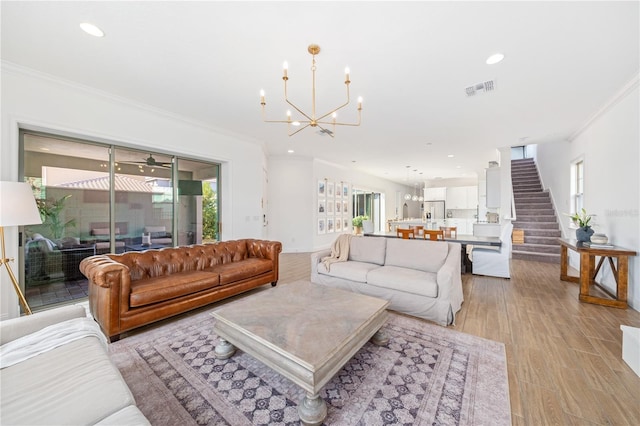 living room with ornamental molding, a chandelier, and light wood-type flooring