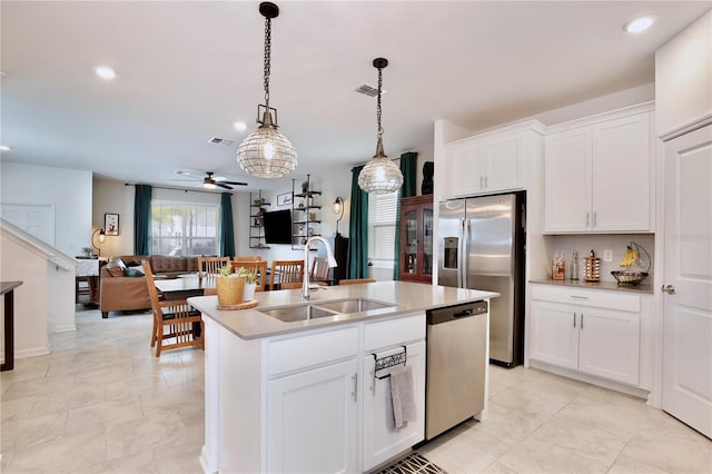 kitchen featuring appliances with stainless steel finishes, decorative light fixtures, white cabinetry, sink, and a center island with sink