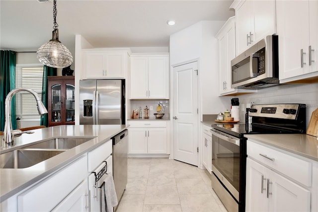 kitchen featuring pendant lighting, sink, appliances with stainless steel finishes, white cabinets, and decorative backsplash