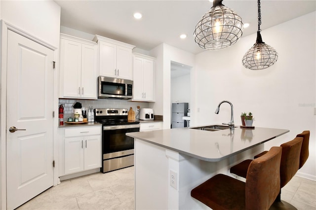 kitchen featuring sink, an island with sink, pendant lighting, stainless steel appliances, and white cabinets