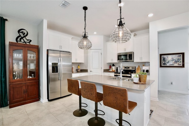 2429 Volunteer Ave, Kissimmee, FL 34744 - kitchen featuring an island with sink, pendant lighting, white cabinets, and appliances with stainless steel finishes