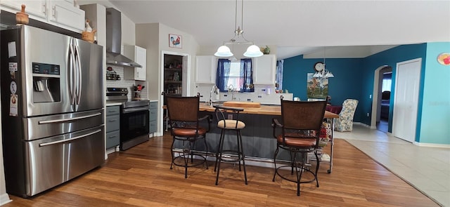 kitchen with white cabinetry, an inviting chandelier, appliances with stainless steel finishes, pendant lighting, and wall chimney range hood