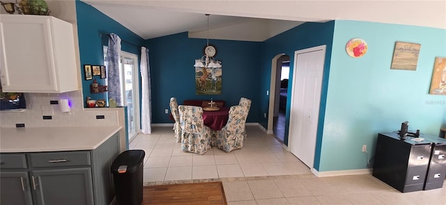 dining space featuring lofted ceiling, light tile patterned floors, and an inviting chandelier