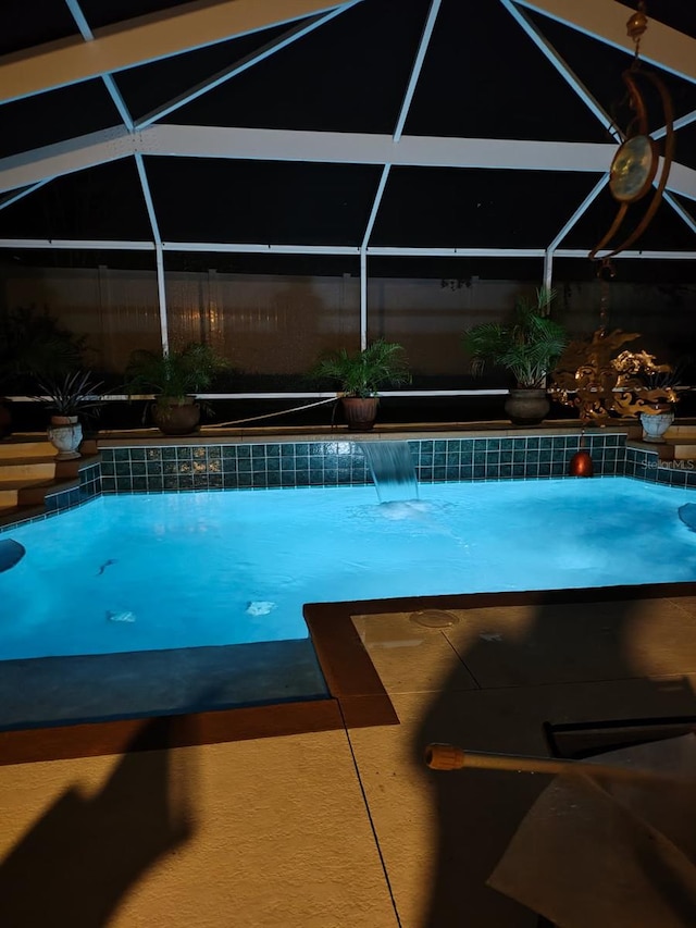 view of pool with pool water feature and glass enclosure