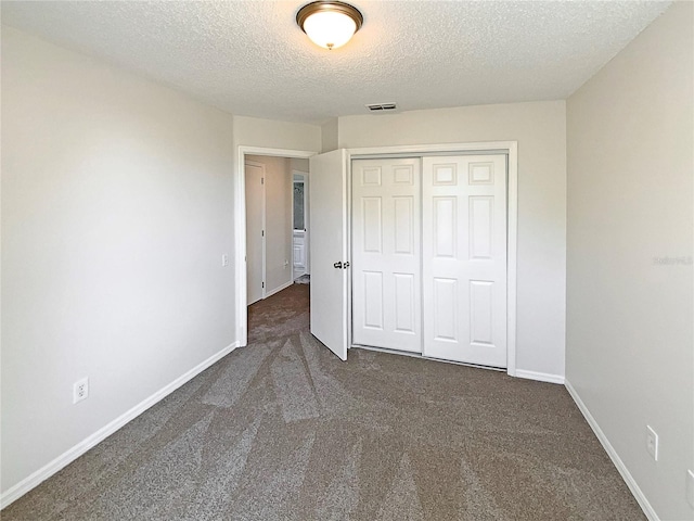 unfurnished bedroom featuring dark carpet, a closet, and a textured ceiling