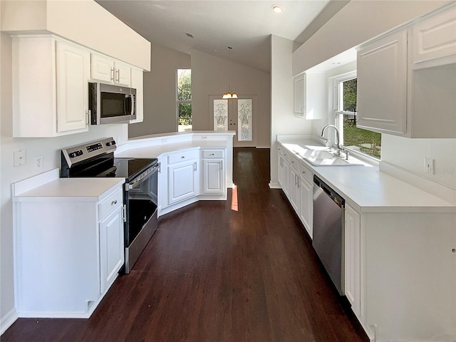 kitchen featuring lofted ceiling, appliances with stainless steel finishes, kitchen peninsula, pendant lighting, and white cabinets