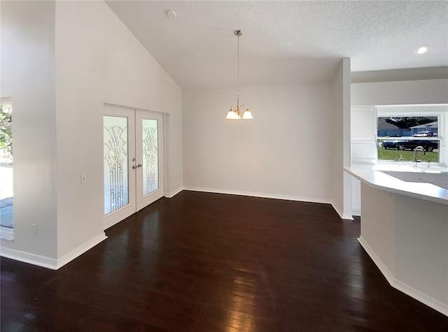 interior space with high vaulted ceiling, a notable chandelier, dark wood-type flooring, a textured ceiling, and french doors