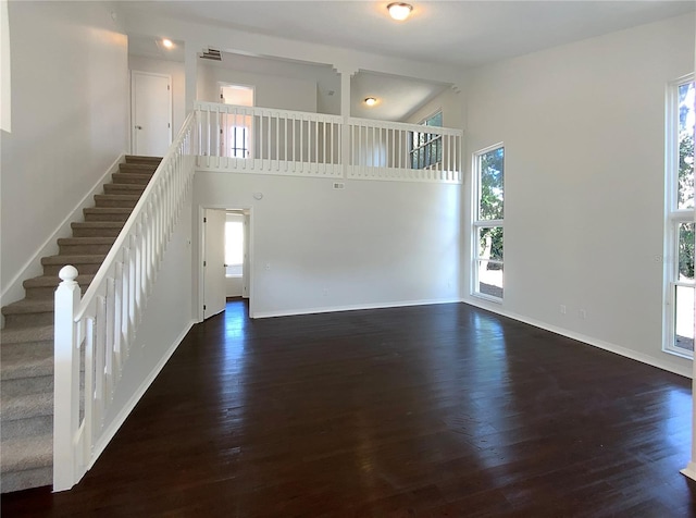 unfurnished living room featuring dark wood-type flooring and high vaulted ceiling