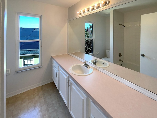 full bathroom featuring tiled shower / bath, vanity, and toilet