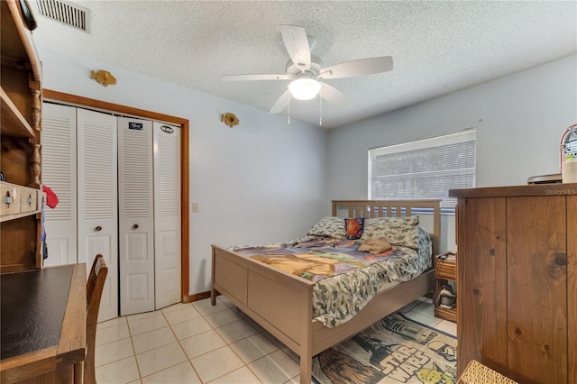 bedroom featuring a textured ceiling, ceiling fan, light tile patterned flooring, visible vents, and a closet