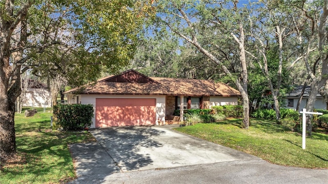 single story home with an attached garage, brick siding, driveway, and a front yard