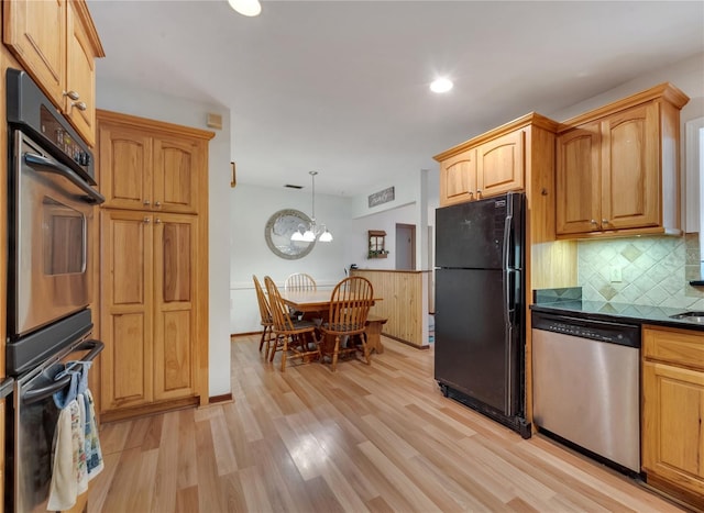 kitchen featuring light wood-style flooring, hanging light fixtures, appliances with stainless steel finishes, tasteful backsplash, and dark countertops