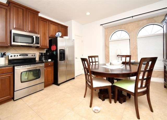 kitchen with decorative backsplash, stainless steel appliances, and light tile patterned flooring