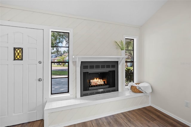 interior space with a lit fireplace, wood finished floors, and baseboards