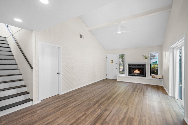 unfurnished living room featuring lofted ceiling, ceiling fan, wood finished floors, a lit fireplace, and stairs