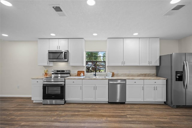 kitchen featuring appliances with stainless steel finishes, dark wood-style flooring, a sink, and visible vents