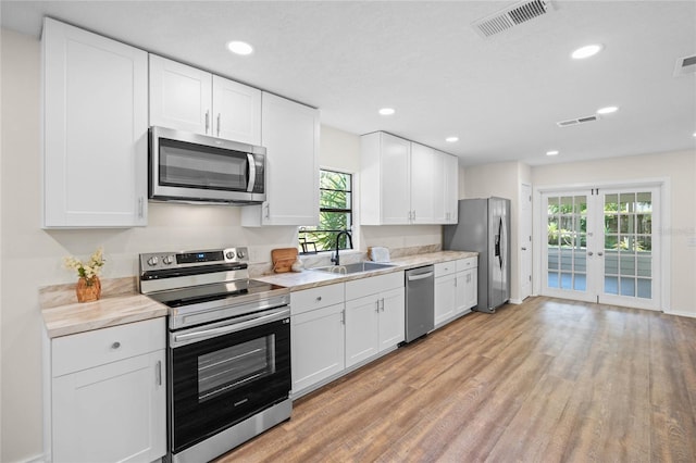 kitchen featuring appliances with stainless steel finishes, light wood-type flooring, light countertops, and a sink