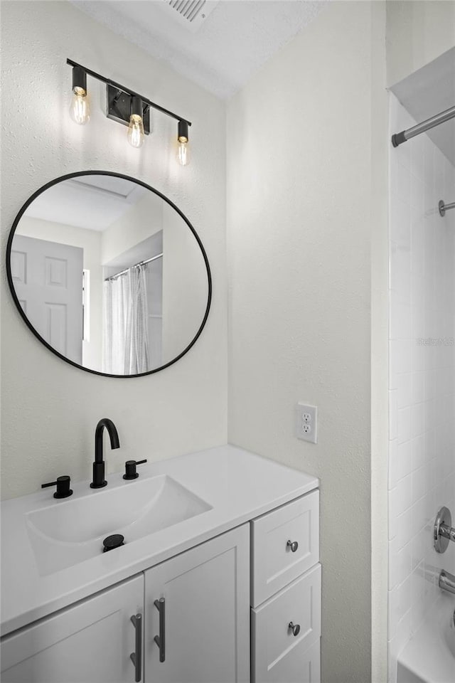 bathroom featuring visible vents, a textured wall, vanity, and shower / tub combo with curtain