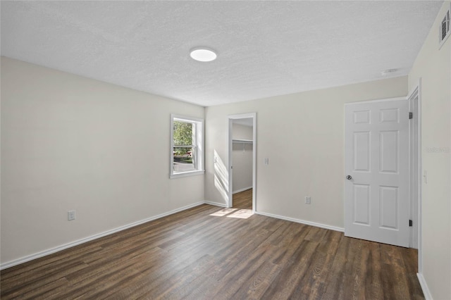 unfurnished bedroom featuring visible vents, baseboards, dark wood-type flooring, a textured ceiling, and a closet