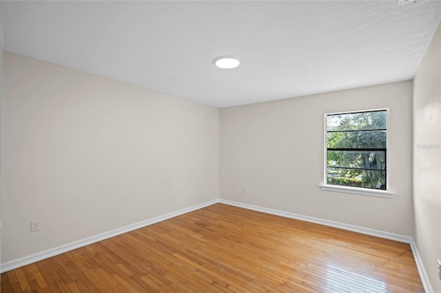 spare room featuring wood-type flooring and baseboards