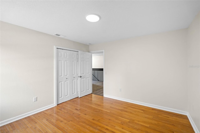 unfurnished bedroom with light wood finished floors, a closet, visible vents, and baseboards