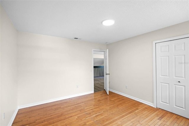 unfurnished bedroom featuring light wood-type flooring, visible vents, and baseboards