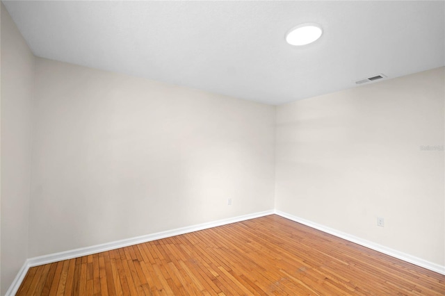 unfurnished room with hardwood / wood-style flooring, visible vents, and baseboards