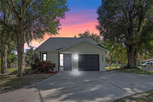 view of front of home with a garage, a shingled roof, and concrete driveway