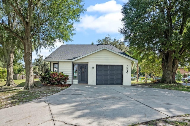 view of front of property featuring a garage, driveway, and a shingled roof