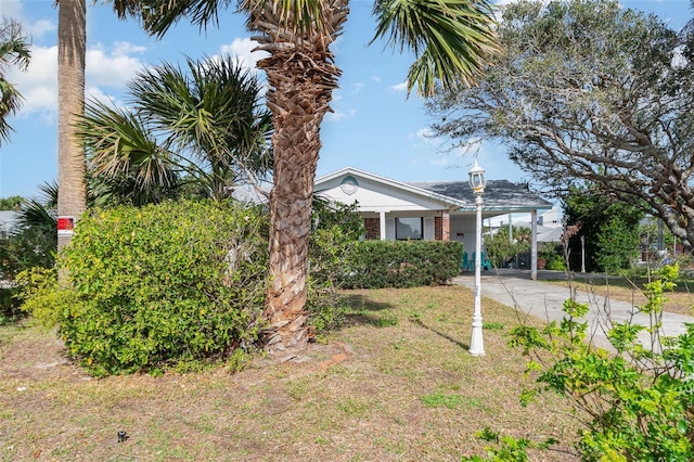 view of side of property featuring a carport, driveway, a yard, and brick siding