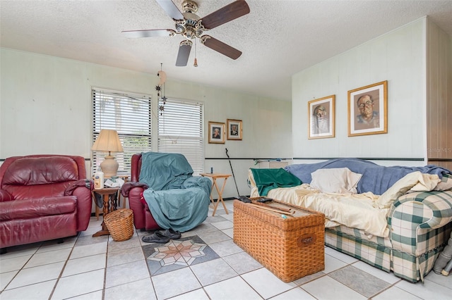 living area with light tile patterned flooring, ceiling fan, and a textured ceiling