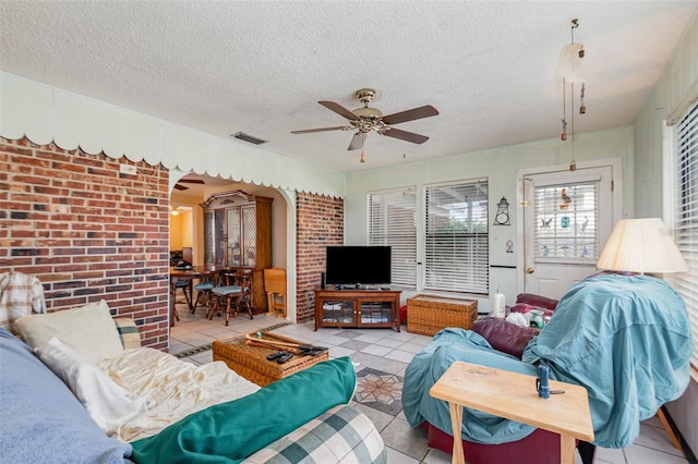 living area featuring arched walkways, a textured ceiling, light tile patterned flooring, and visible vents