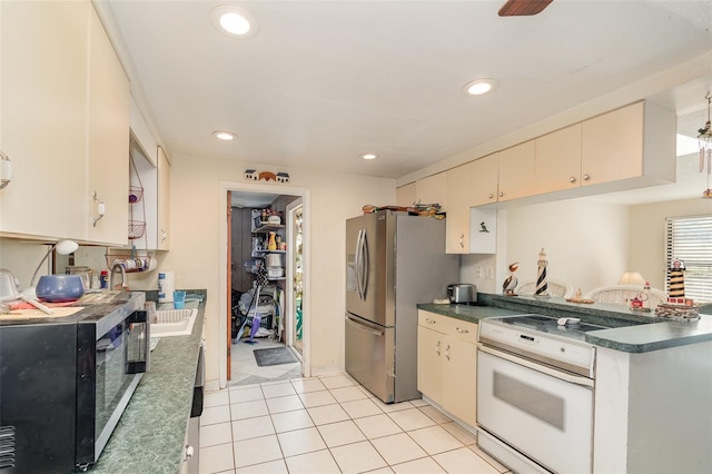 kitchen featuring appliances with stainless steel finishes, dark countertops, cream cabinets, and recessed lighting