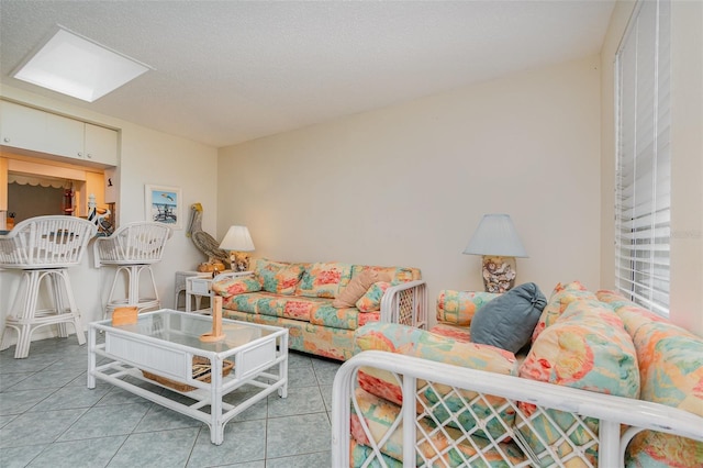 living room with a skylight, a textured ceiling, and light tile patterned floors