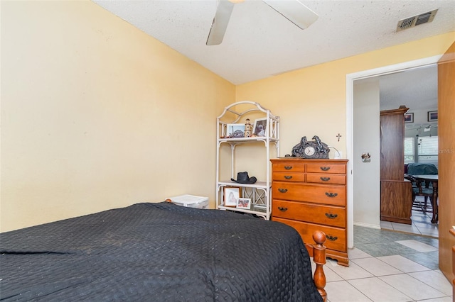 bedroom with ceiling fan, a textured ceiling, light tile patterned flooring, and visible vents