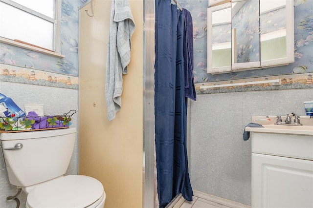 bathroom with curtained shower, vanity, toilet, and wallpapered walls