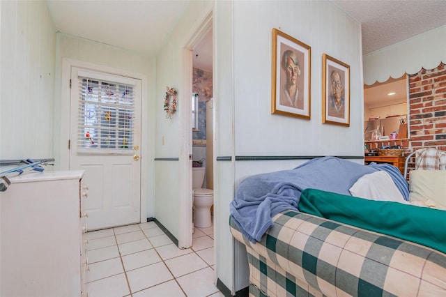 bedroom featuring connected bathroom, a textured ceiling, and light tile patterned floors