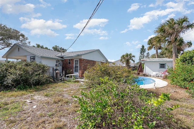 rear view of house featuring a fenced in pool and brick siding