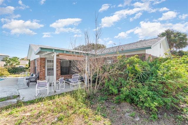 rear view of house with brick siding and a patio