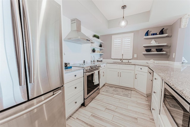 kitchen with sink, light stone countertops, stainless steel appliances, range hood, and white cabinets