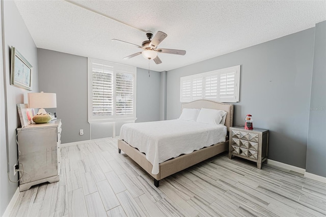 bedroom featuring ceiling fan, light hardwood / wood-style floors, and a textured ceiling