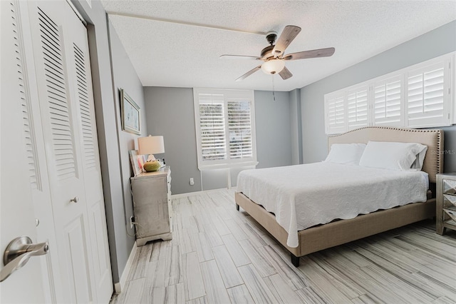 bedroom featuring ceiling fan, a closet, a textured ceiling, and light wood-type flooring