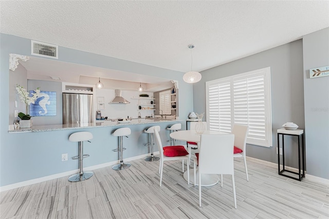 dining room featuring sink, a textured ceiling, and light wood-type flooring