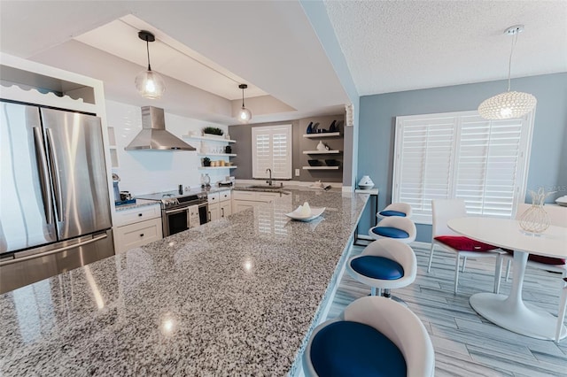 kitchen featuring a breakfast bar, light stone counters, appliances with stainless steel finishes, pendant lighting, and island exhaust hood